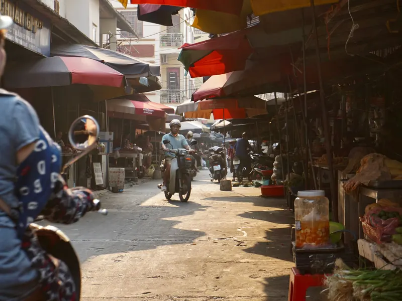 Ruelle d'un marché local de Ha Giang avec motos et parasols
